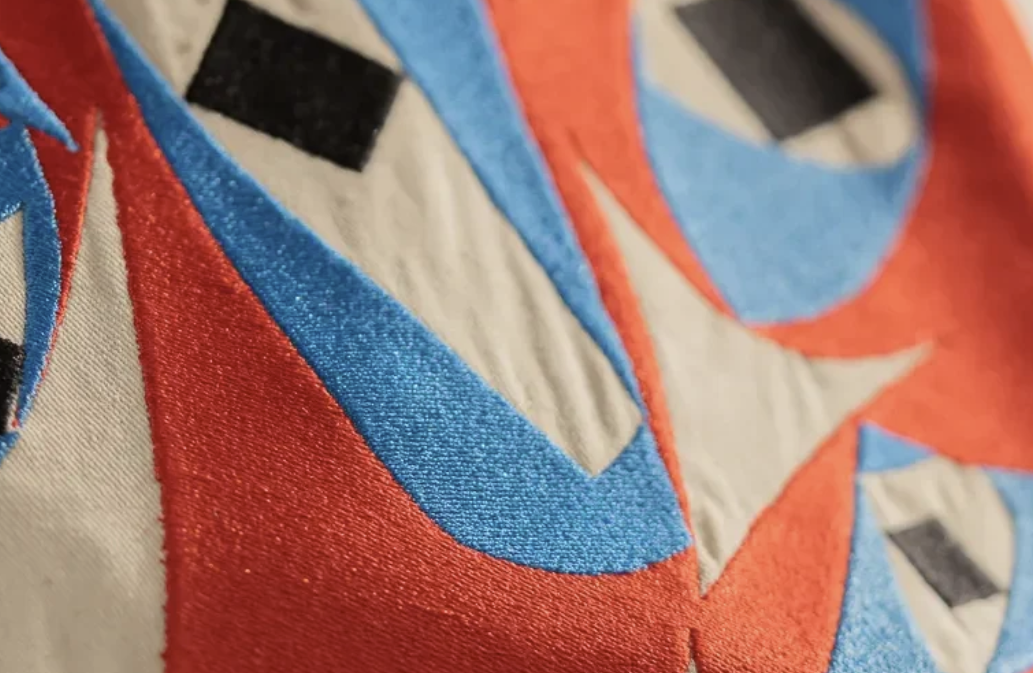 A close-up of colourful Thaana lettering on fabric